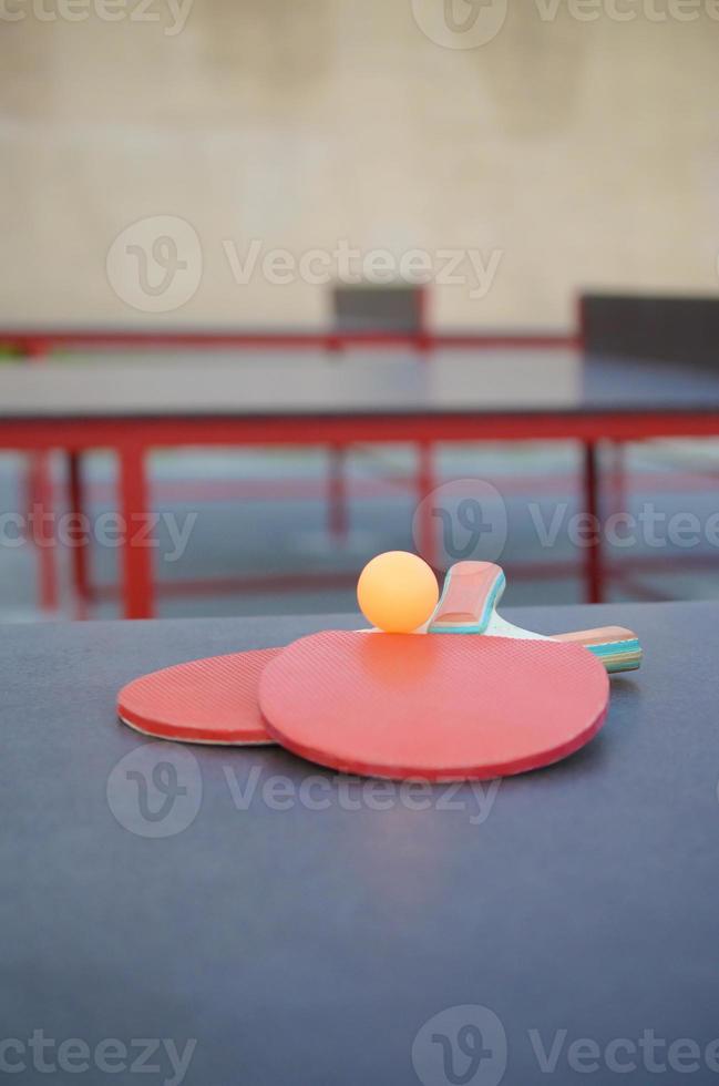 raquetes e bola na mesa de pingue-pongue no pátio de esportes ao ar livre. esportes ativos e conceito de treinamento físico foto