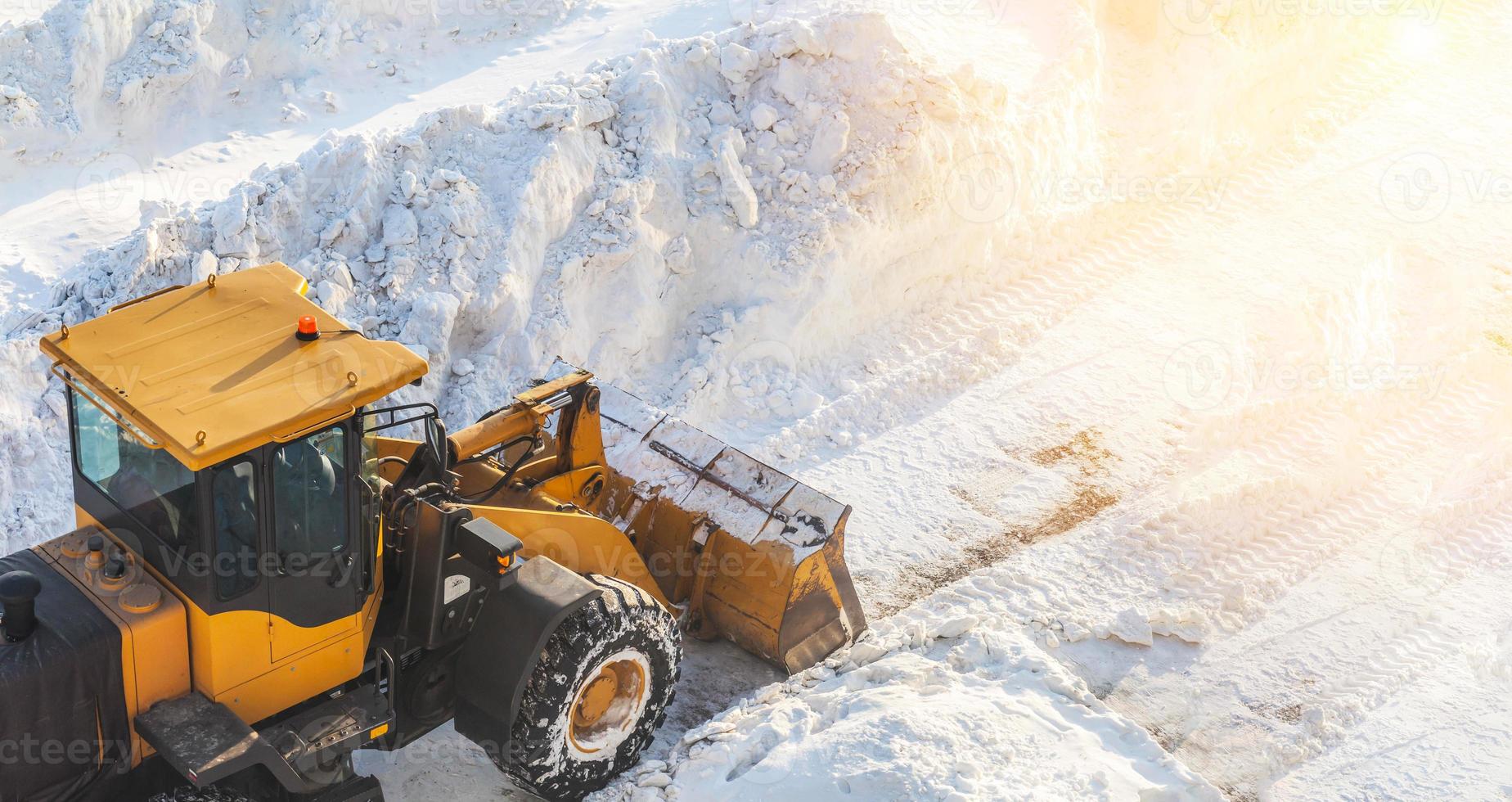 limpeza de neve. trator abre caminho após forte nevasca. um grande trator laranja remove a neve da estrada e limpa a calçada. limpando estradas na cidade da neve no inverno. foto