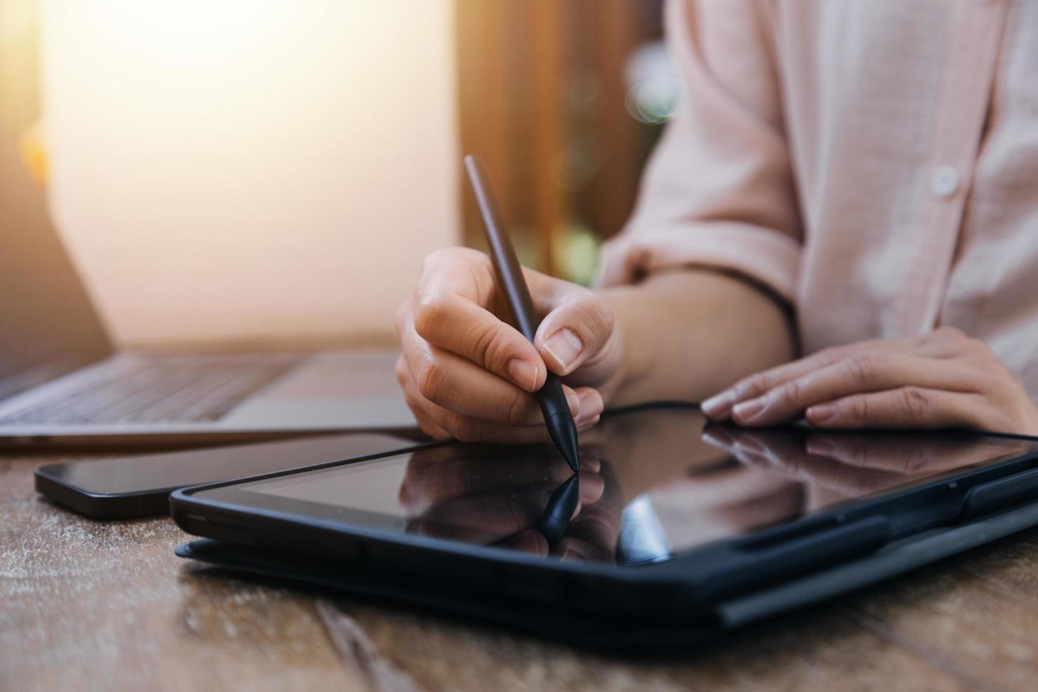 mão de empresária trabalhando com computador portátil, tablet e telefone inteligente no escritório moderno com diagrama de ícone virtual no modernoffice na luz da manhã foto