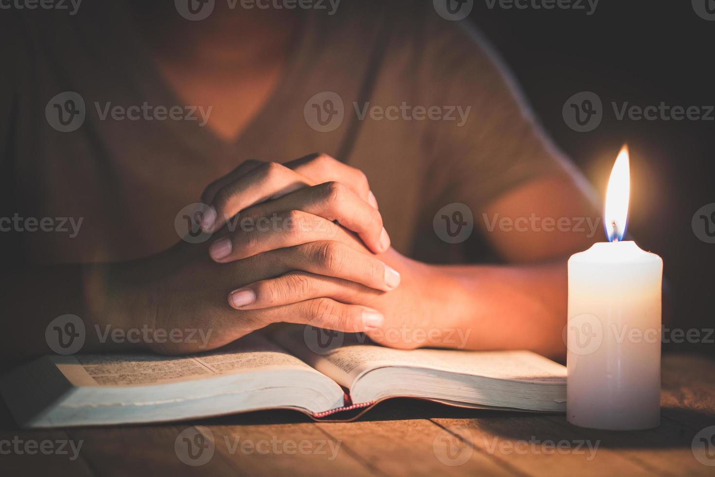 menino de mão rezando na sala e velas acesas à luz, mãos cruzadas no conceito de oração para fé, espiritualidade e religião foto