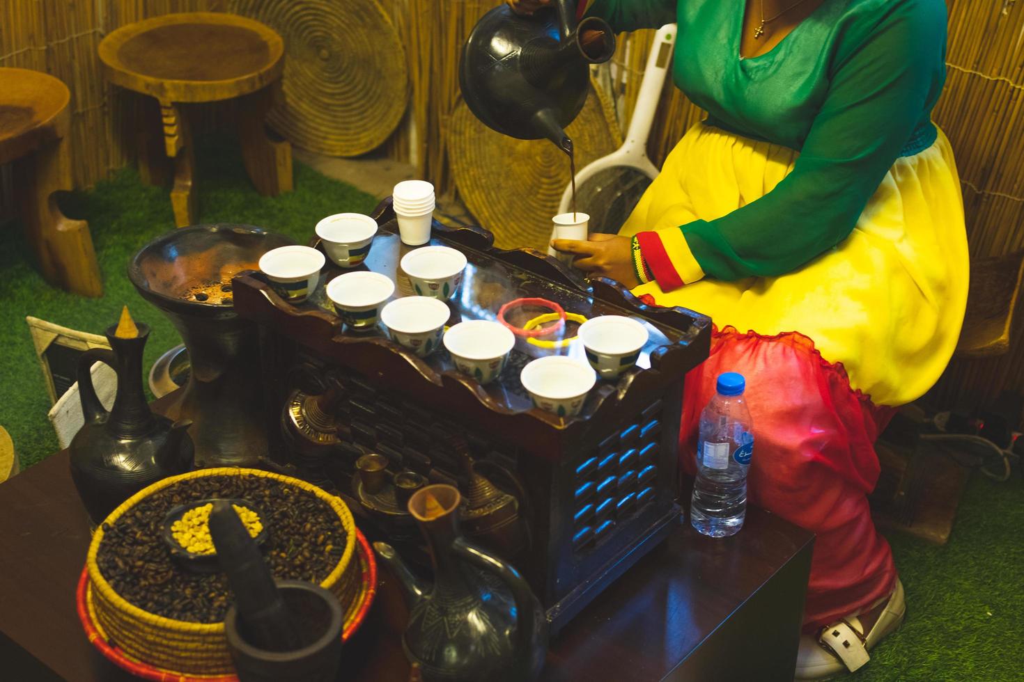 dubai, emirados árabes unidos, 2022 - senhora africana derrama café tradicional na xícara do pote. métodos antigos de preparação de café com tecnologia vintage foto