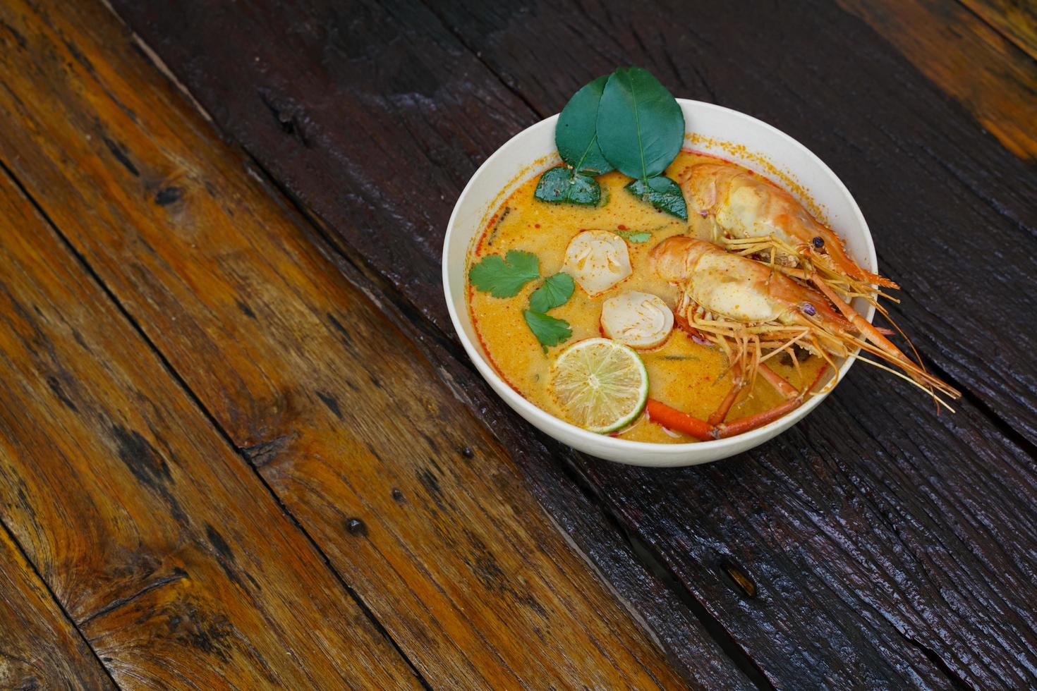 tom yum kung em um copo no chão de madeira, tom yum kung também é o prato nacional da tailândia. e é um alimento que é famoso em todo o mundo. foto