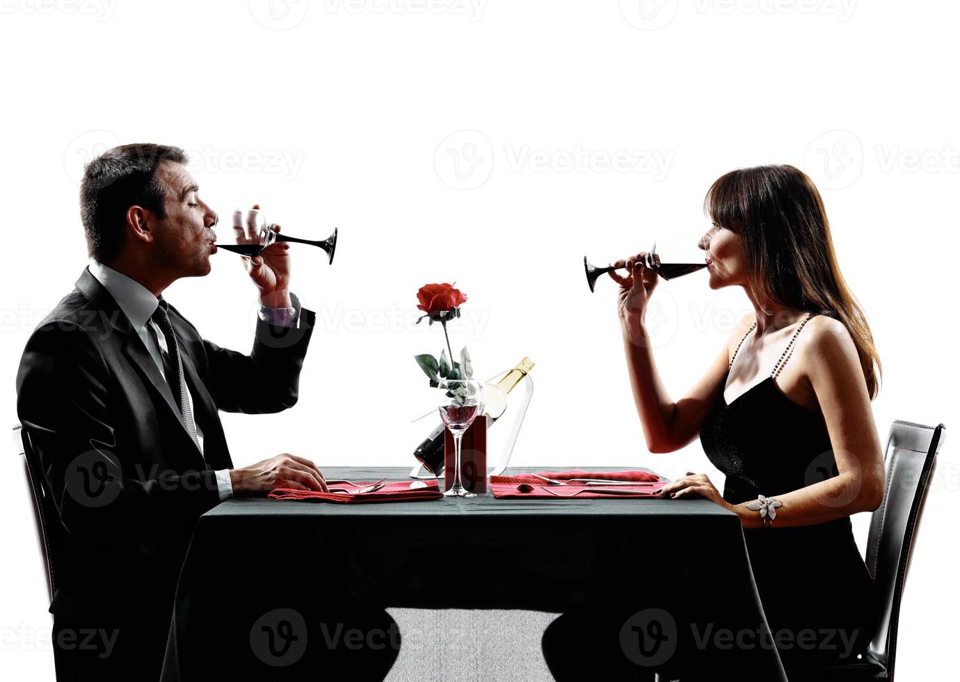 casais amantes bebendo vinho no jantar silhuetas foto