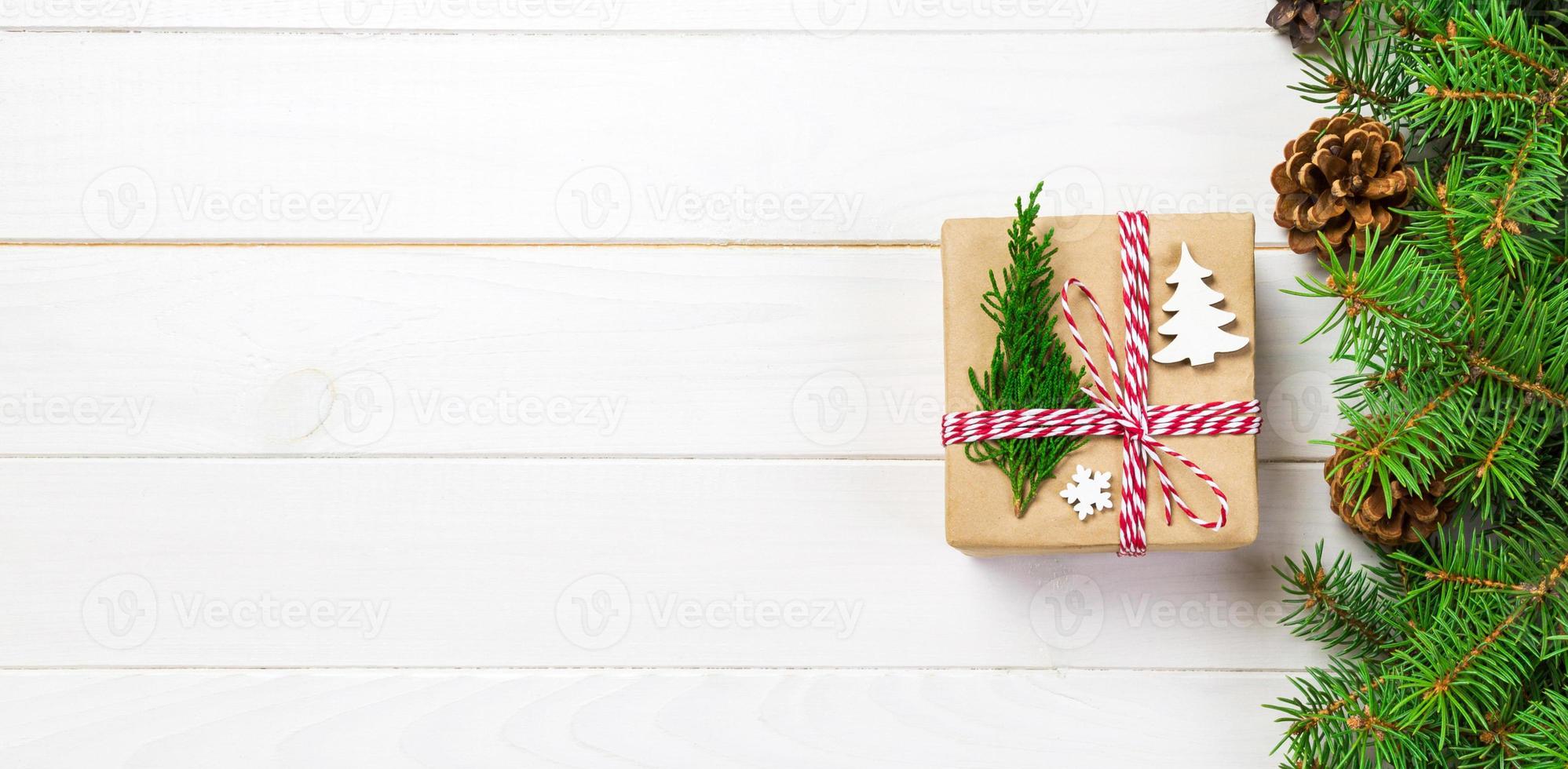 caixa de presente de natal embrulhada em papel reciclado, banner com laço de fita, com fita em fundo rústico. conceito de férias foto