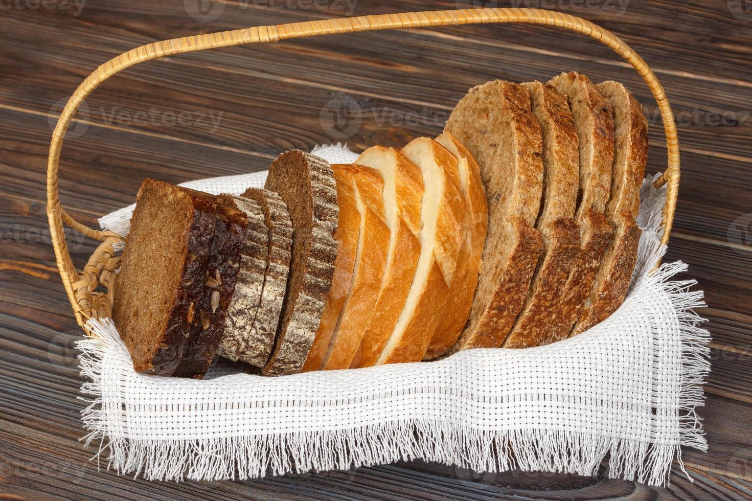 cesta com pão fatiado de tipo diferente em fundo de madeira foto