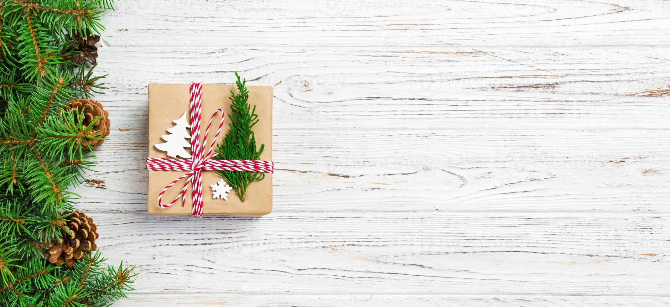 caixa de presente de natal embrulhada em papel reciclado, com laço de fita, com fita em fundo rústico. conceito de banner de férias foto