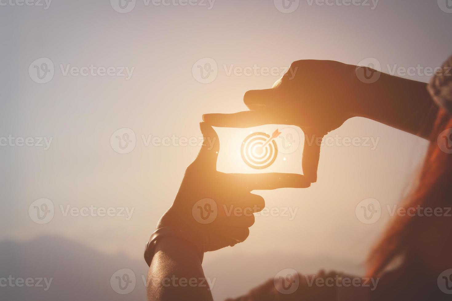 conceito de planejamento e visão do início do ano novo, mão de mulher fazendo gesto de quadro encontrar foco ao pôr do sol, mulher procurando perspectiva para capturar o significado de um alvo próximo claro. foto