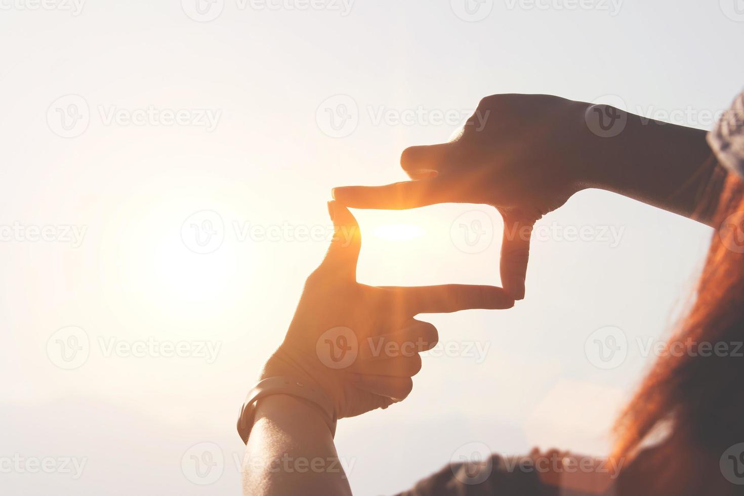 conceito de planejamento e visão do início do ano novo, mãos de mulher fazendo gesto de quadro encontram foco ao pôr do sol, mulher procurando perspectiva para capturar o significado de um alvo próximo claro. foto