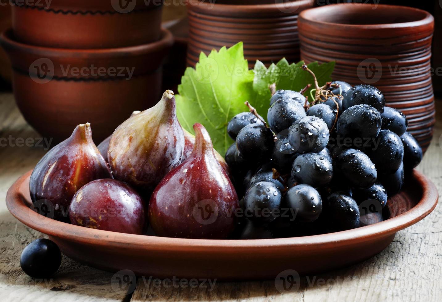 figos e uvas maduros em um prato de barro foto