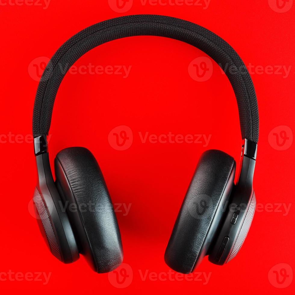 fones de ouvido sem fio pretos em um fundo vermelho. fones de ouvido de nível profissional isolados para DJs e músicos foto