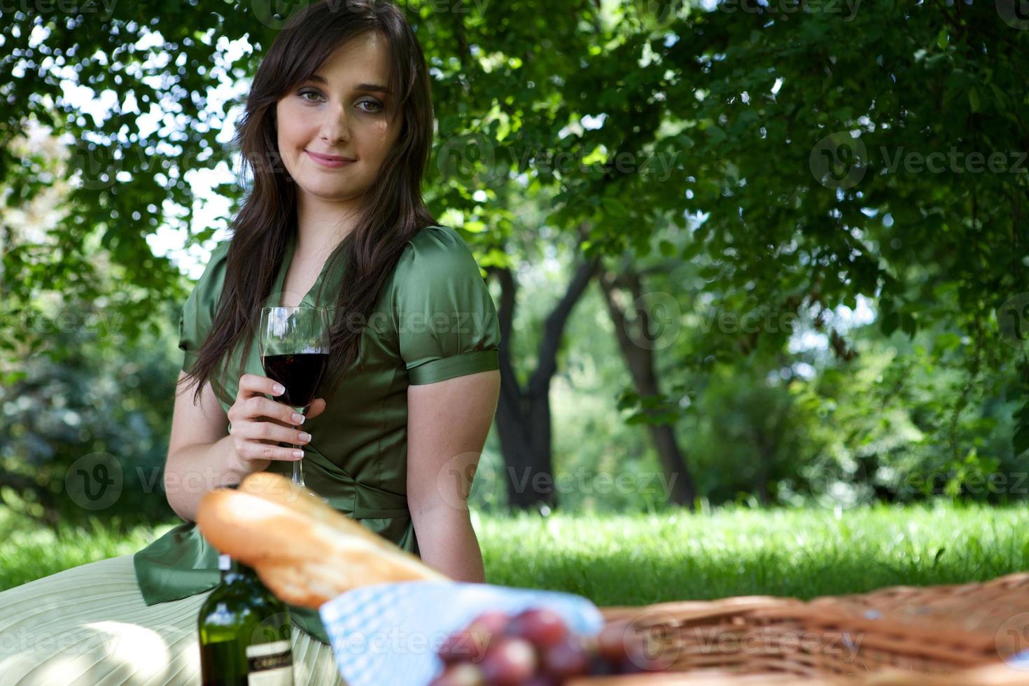retrato de jovem segurando um copo de vinho, sentado no parque foto