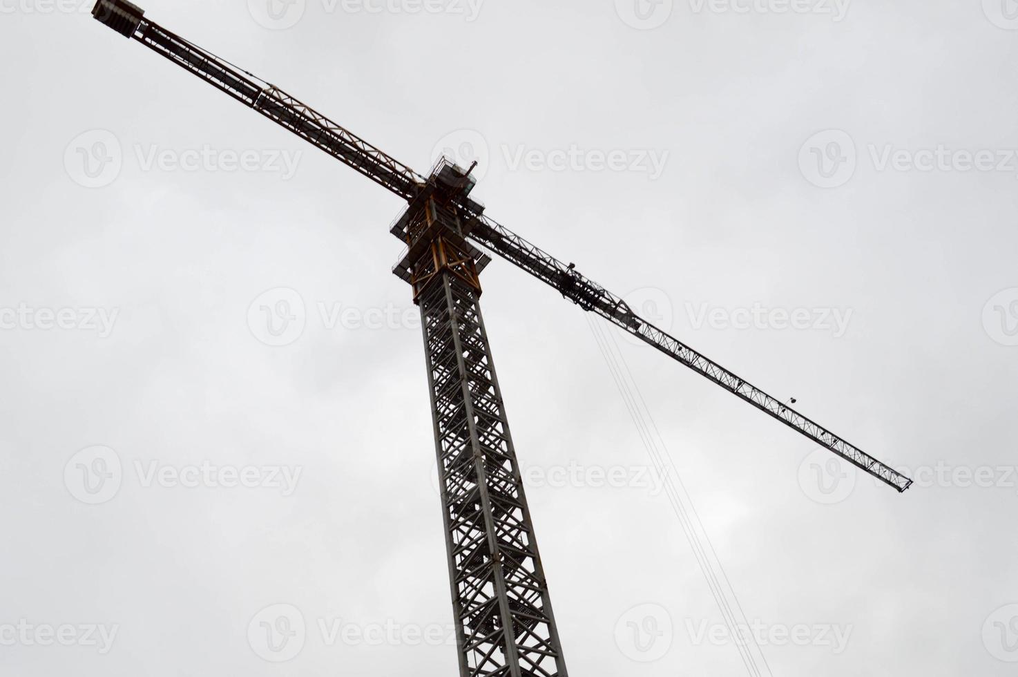 grande guindaste industrial de carga de construção poderoso em um canteiro de obras de novos edifícios e casas contra o céu foto