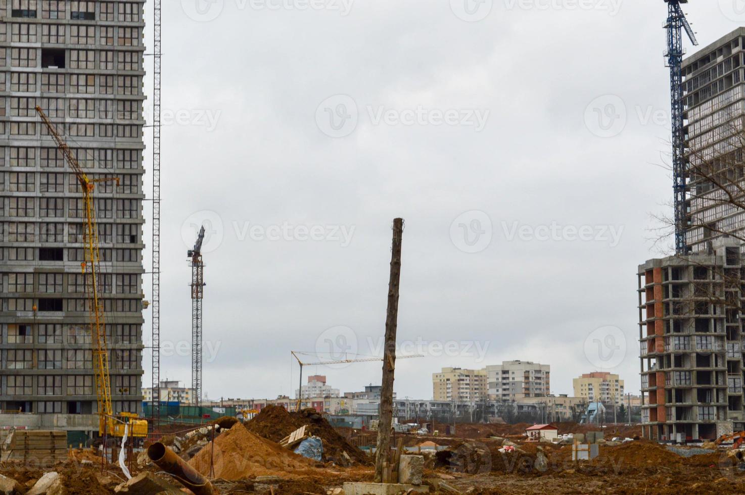 construção de grandes casas de estrutura monolíticas modernas, edifícios usando equipamentos de construção industrial e grandes guindastes altos. construção do prédio no novo micro distrito da cidade foto