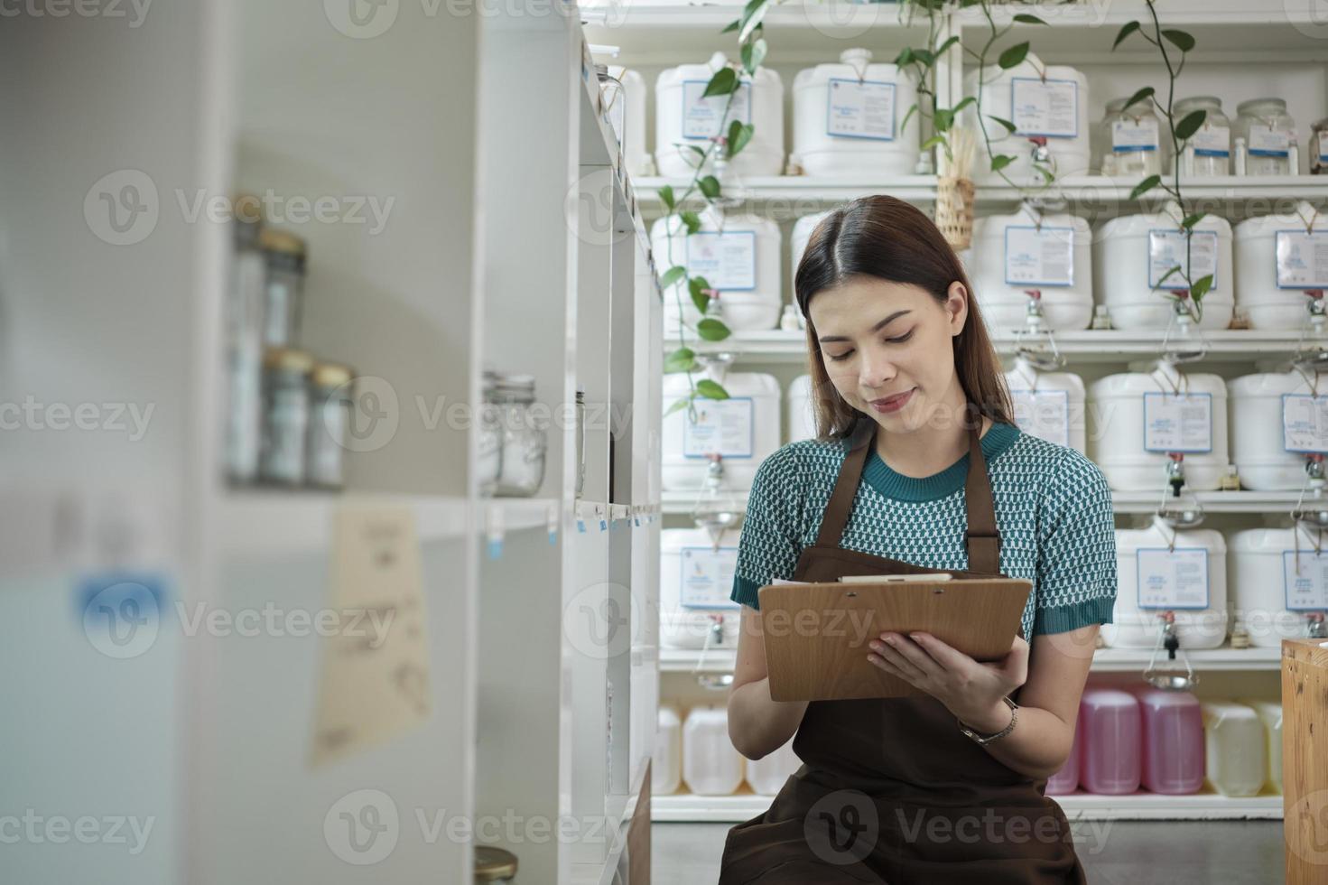 lojista branca verifica o estoque de produtos orgânicos naturais na exibição de varejo na loja de refil, mercearia sem desperdício e sem plástico, estilos de vida ecológicos e sustentáveis, recipientes reutilizáveis. foto