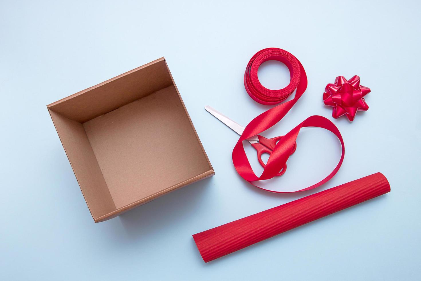 caixa de presente aberta, tesoura, fita, papel de embrulho, laços para decorar foto