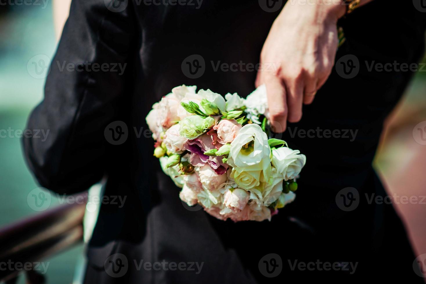 a noiva tem um buquê de casamento nas mãos, flores do dia do casamento. foto