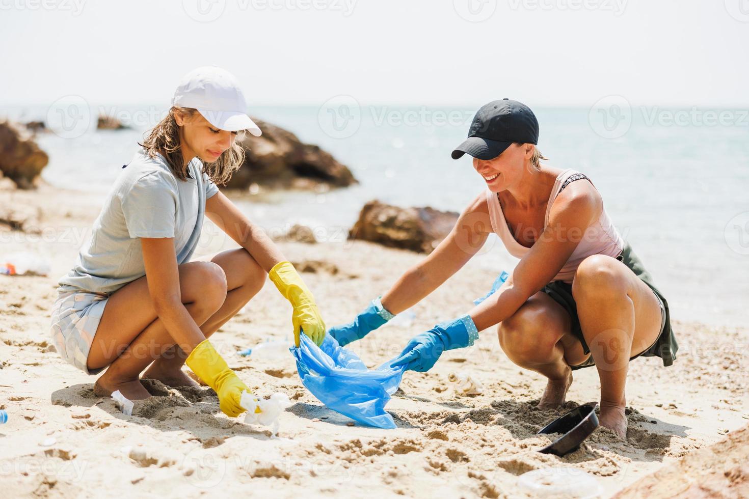 mãe e filha limpando a praia foto