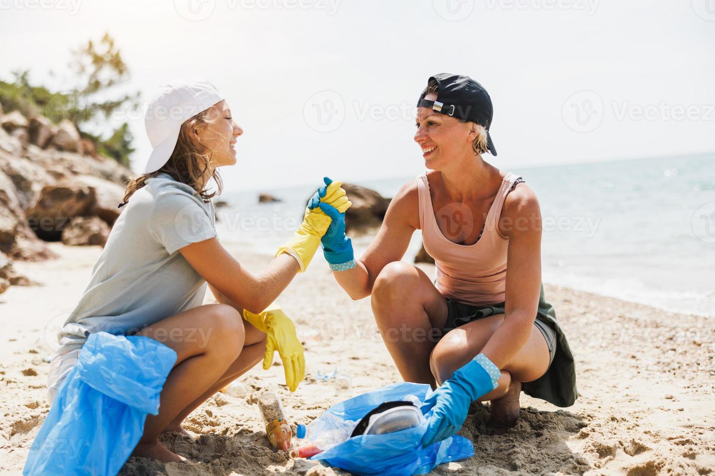 mãe e filha limpando a praia foto