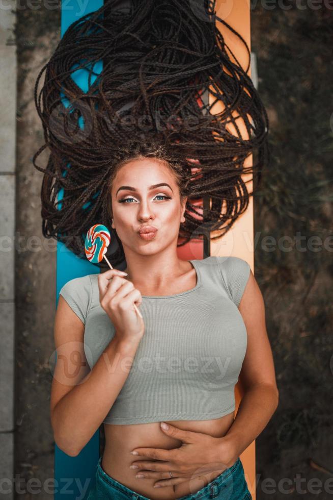 mulher com longas tranças afro se divertindo no banco do parque foto