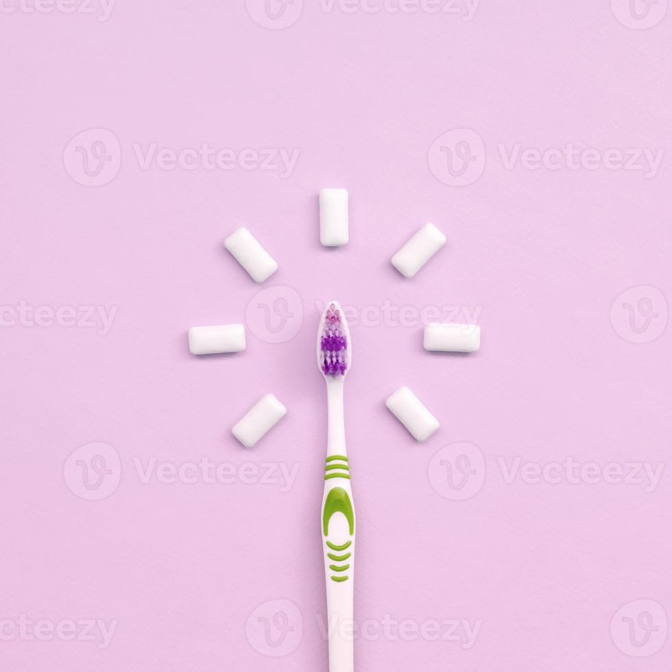 escova de dentes e gomas de mascar estão em um fundo rosa pastel foto