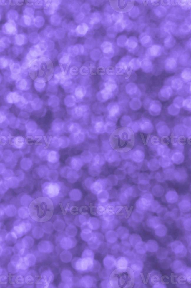 lantejoulas decorativas violetas borradas. imagem de fundo com luzes de bokeh brilhantes de pequenos elementos foto