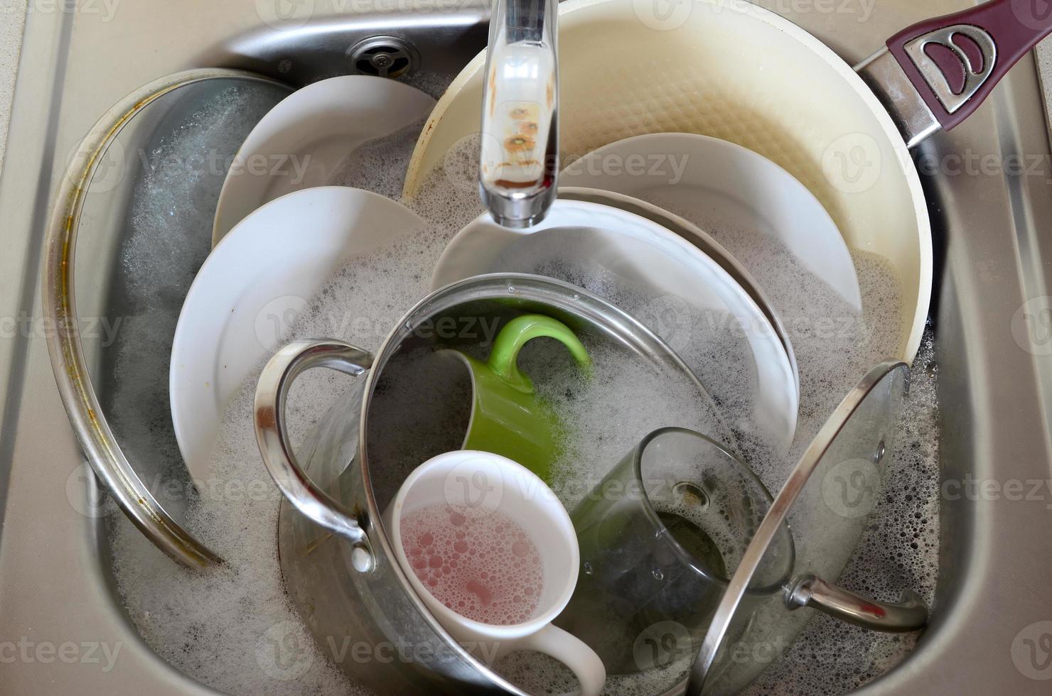 pratos sujos e utensílios de cozinha não lavados enchiam a pia da cozinha foto