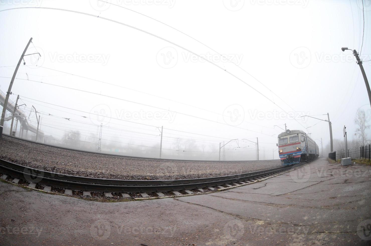 o trem suburbano ucraniano corre ao longo da ferrovia em uma manhã nublada. foto olho de peixe com distorção aumentada