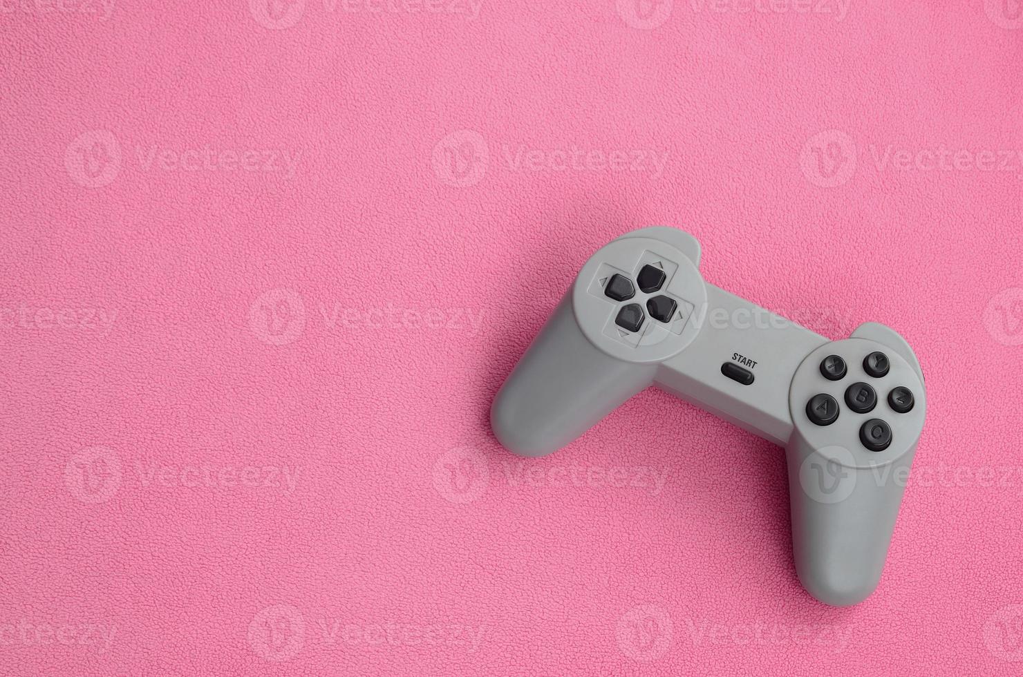 jogando o conceito de jogos. joystick de almofada única encontra-se no cobertor de tecido de lã rosa peludo. controlador para videogames em uma textura de fundo de material de lã macia rosa claro foto