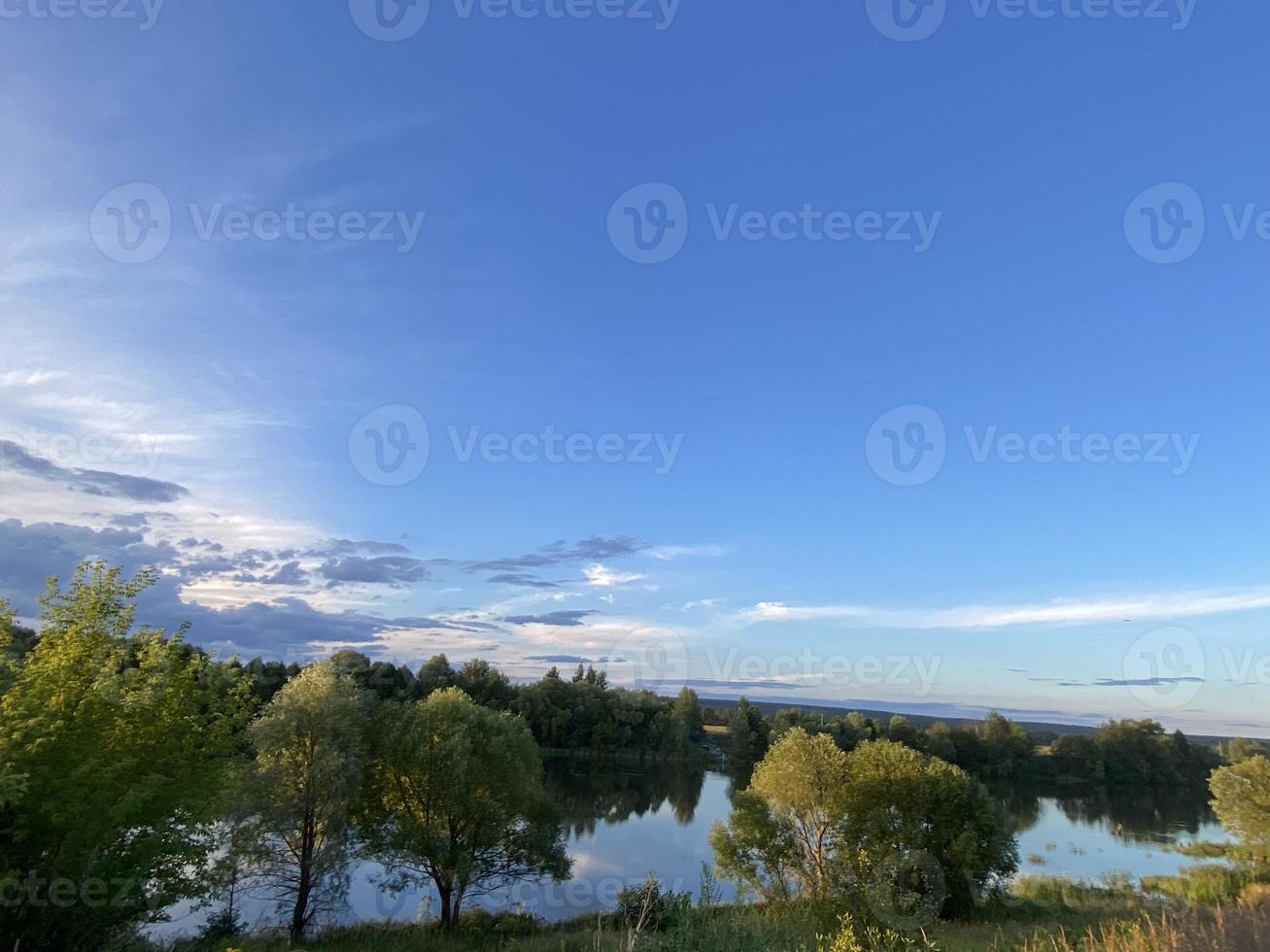 belo pôr do sol no lago. pôr do sol refletido na água - céu azul e laranja com nuvens e árvores em silhueta foto