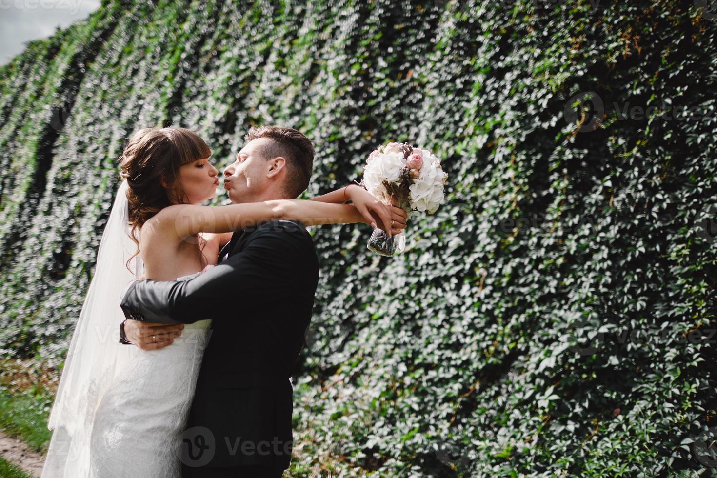 noiva e noivo no dia do casamento caminhando ao ar livre na natureza verde primavera. casal de noivos, mulher recém-casada feliz e homem abraçando no parque verde. amoroso casal de noivos ao ar livre. noiva e noivo foto