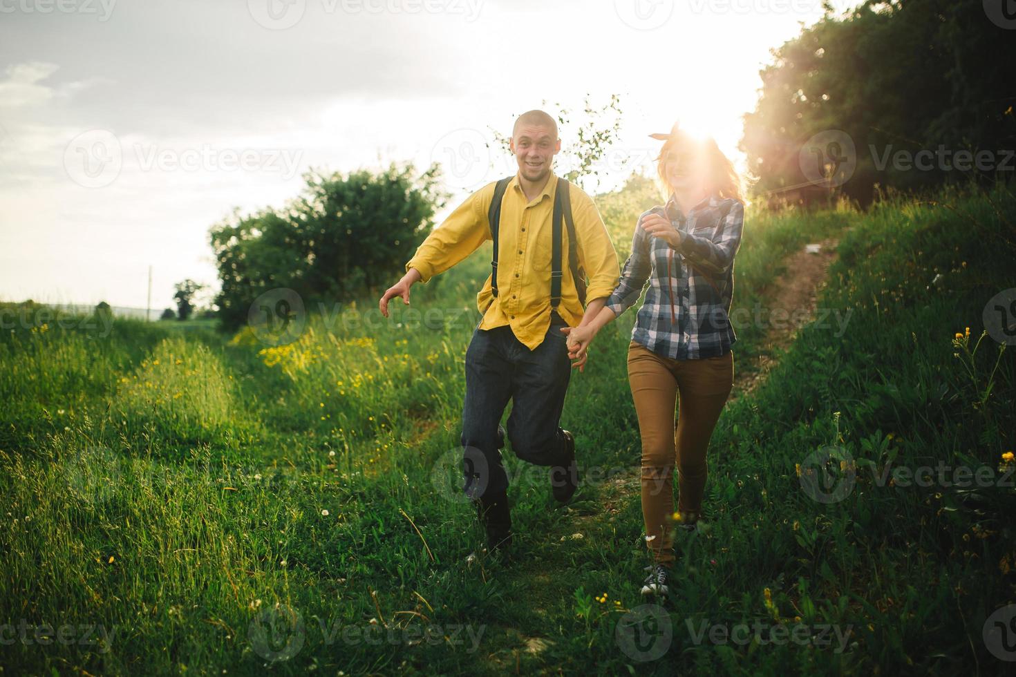 casal hipster amoroso andando no campo, beijando e segurando as mãos, abraçando, deitado na grama no verão ao pôr do sol. Dia dos Namorados foto