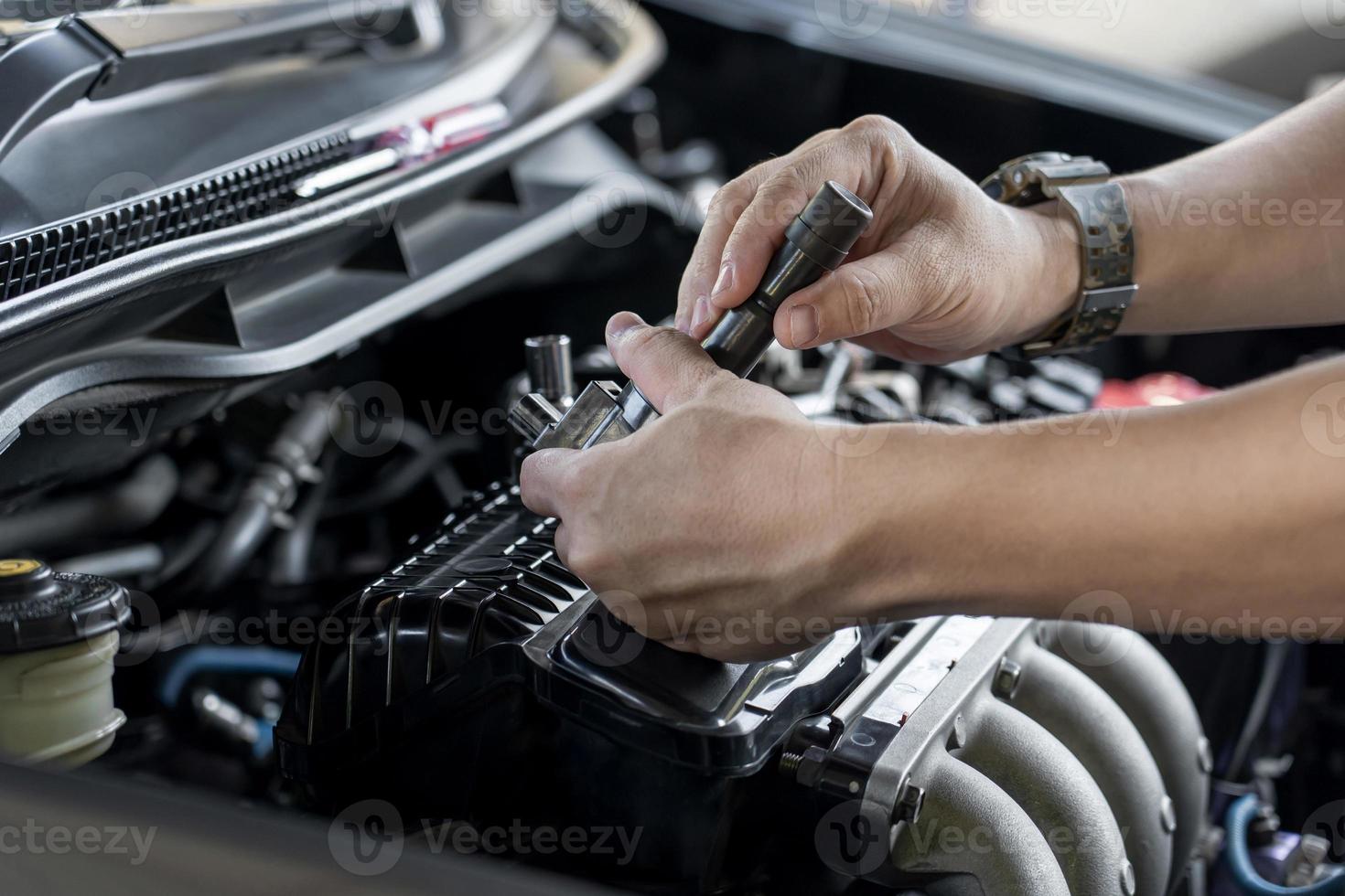 técnico verifica a bobina antiga da vela de ignição com marcas de queimadura na bobina do motor no serviço de manutenção do motor a gasolina na garagem foto