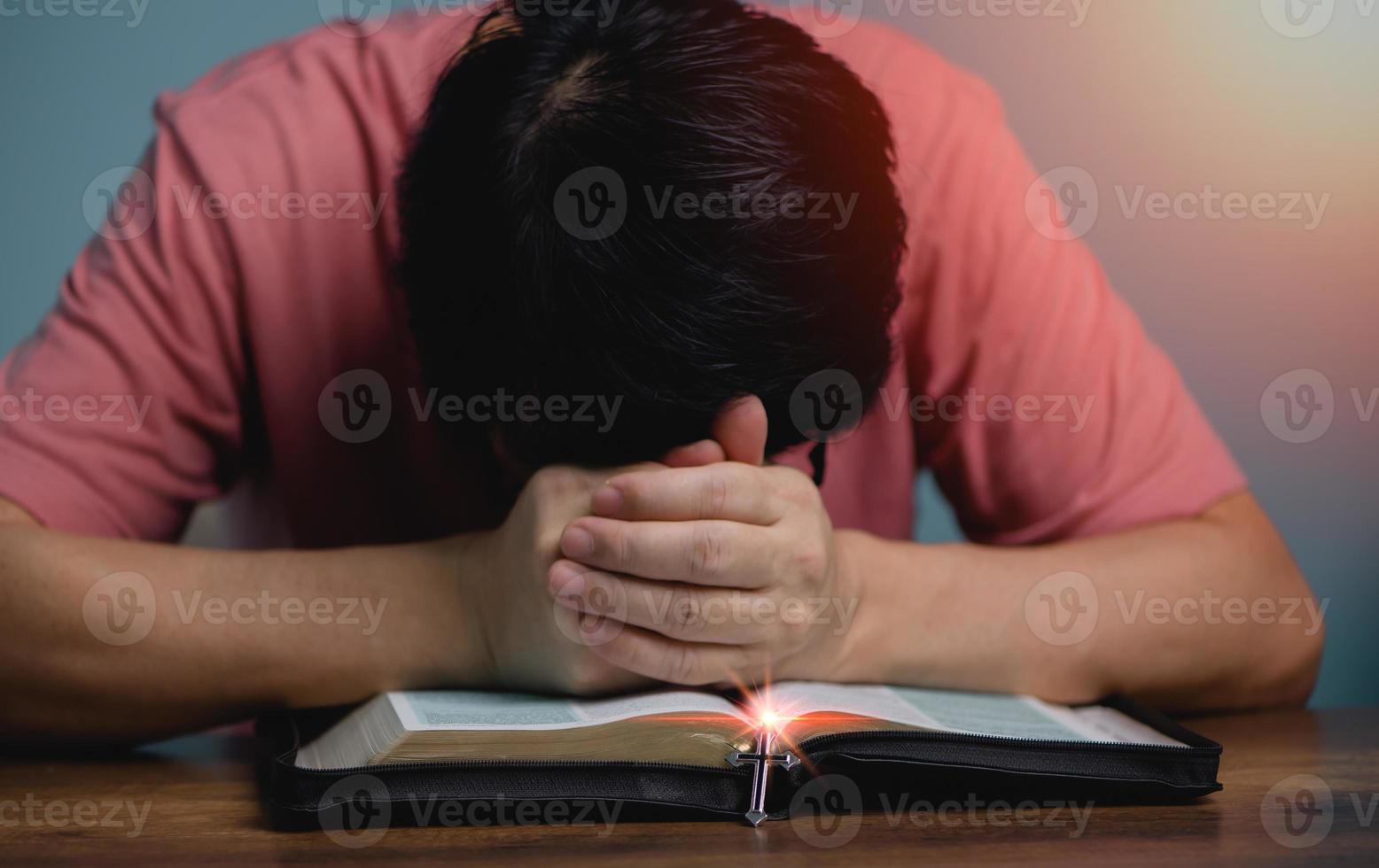 pessoas de mãos dadas, cabeça para baixo, rezar a deus no livro do meio livro da bíblia sagrada com colar cruzado na frente da bíblia sagrada. foto