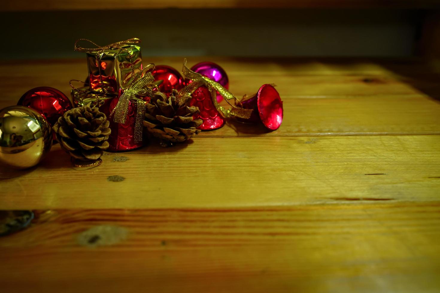 ano novo e decorações temáticas de presente de natal em fundo de madeira, consistindo de uma caixa de presente dourada. bolas coloridas brilhantes pinhas secas e pequenos sinos espaço livre para design foto