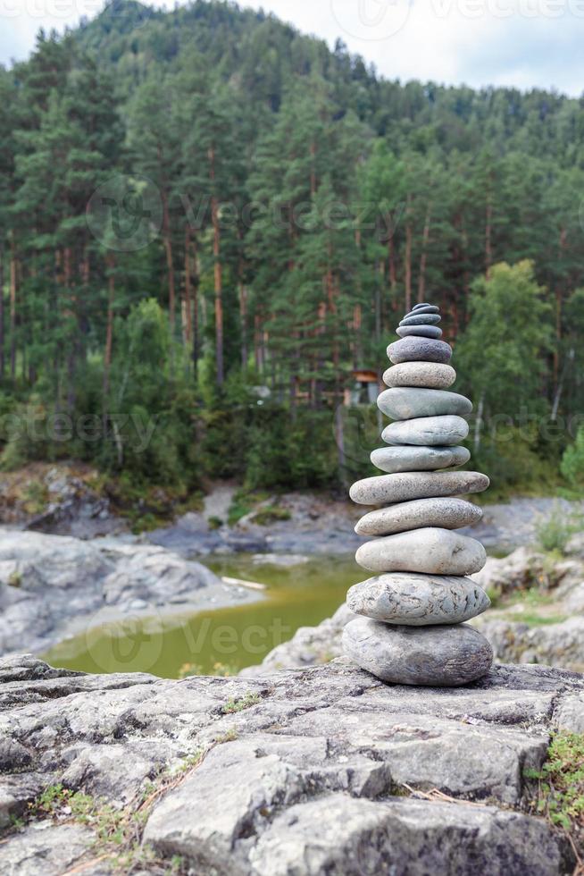 uma pirâmide de pedras nuas empilhadas umas sobre as outras. pedras empilhadas em forma de pirâmide na margem do rio no contexto das montanhas como equilíbrio e equilíbrio na natureza, zen, budismo. foto