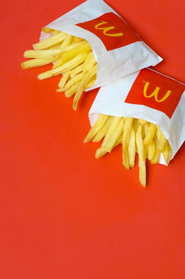 kharkov, ucrânia - 12 de maio de 2022 batatas fritas do mcdonald em pequeno saco de papel em fundo vermelho brilhante foto