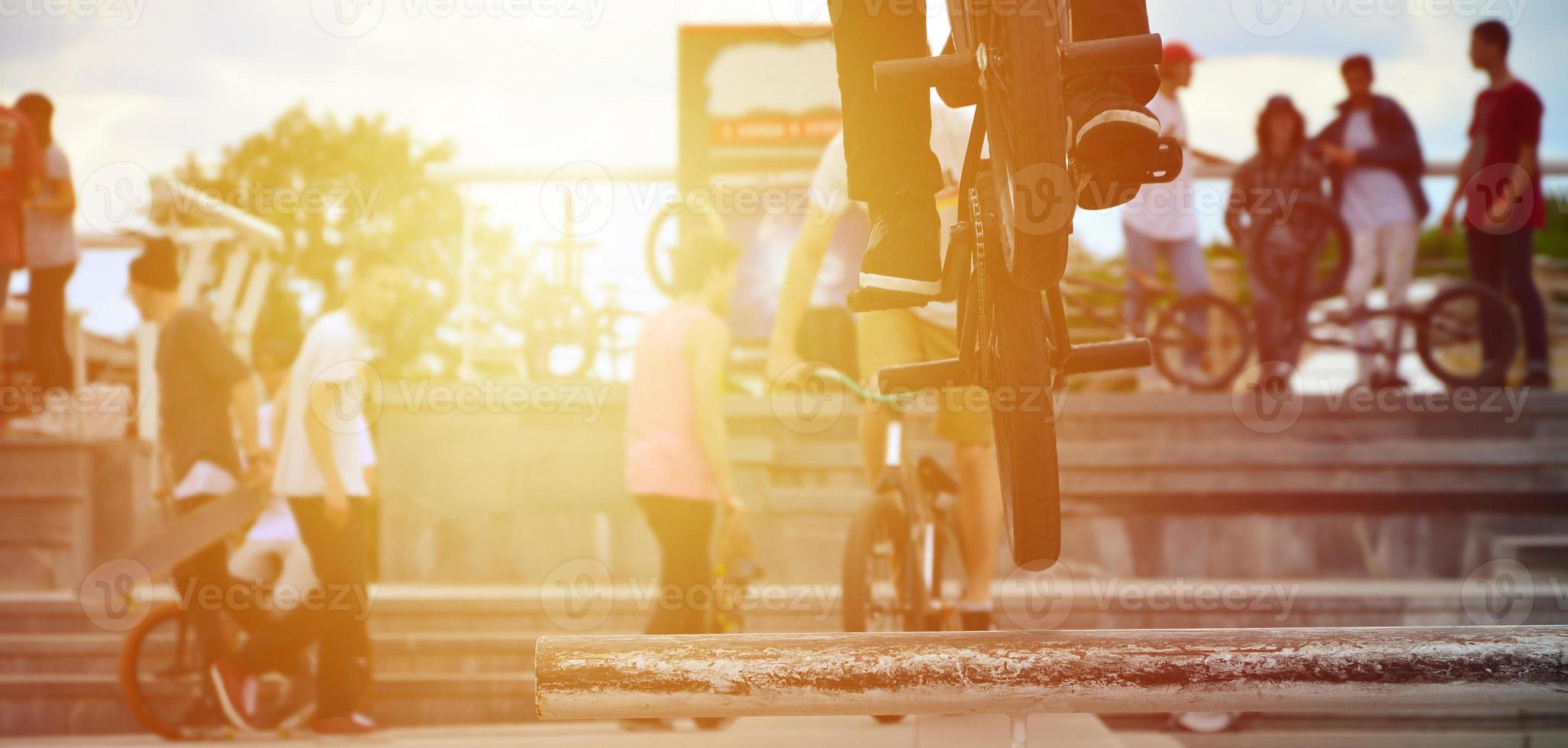 um ciclista salta sobre um cano em uma bicicleta bmx. muitas pessoas com bicicletas ao fundo. conceito de esportes radicais foto