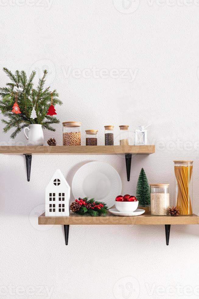 design de interiores confortável e aconchegante de prateleiras de cozinha aberta decoradas para o ano novo e o natal. primeiro plano. parede texturizada branca. foto