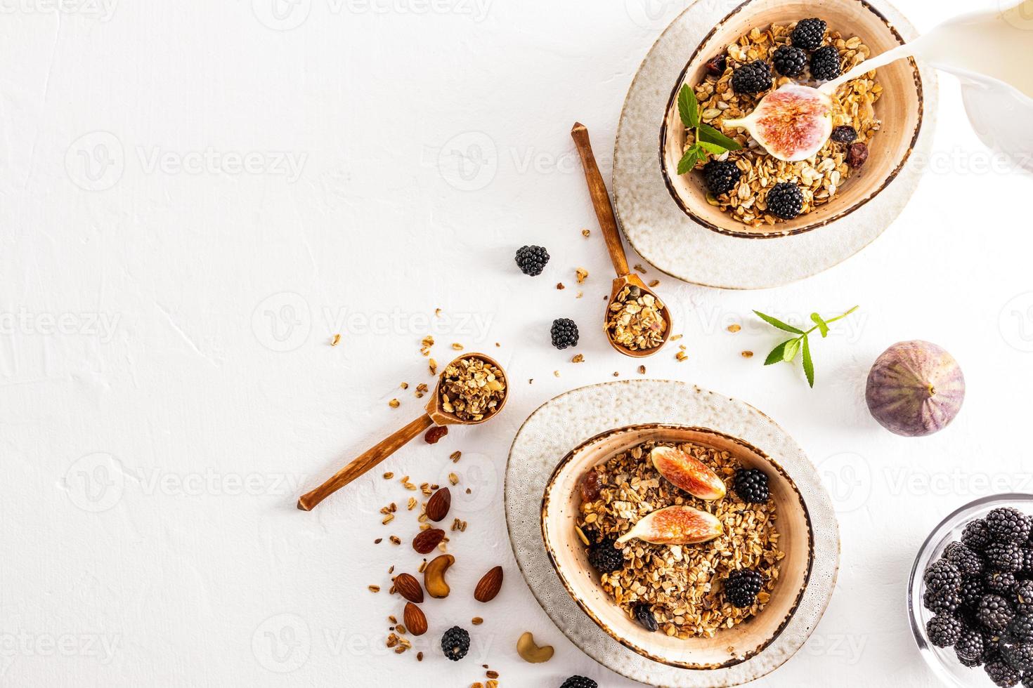 vista superior do fundo branco com duas tigelas de cerâmicas modernas com granola caseira ou muesli, com sementes de chia, nozes, passas e frutas. foto