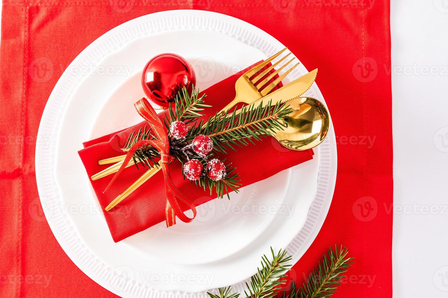 servindo uma mesa de natal com um conjunto de pratos brancos, surfs de mesa de ouro e enfeites de guardanapo de natal. vista do topo. foto