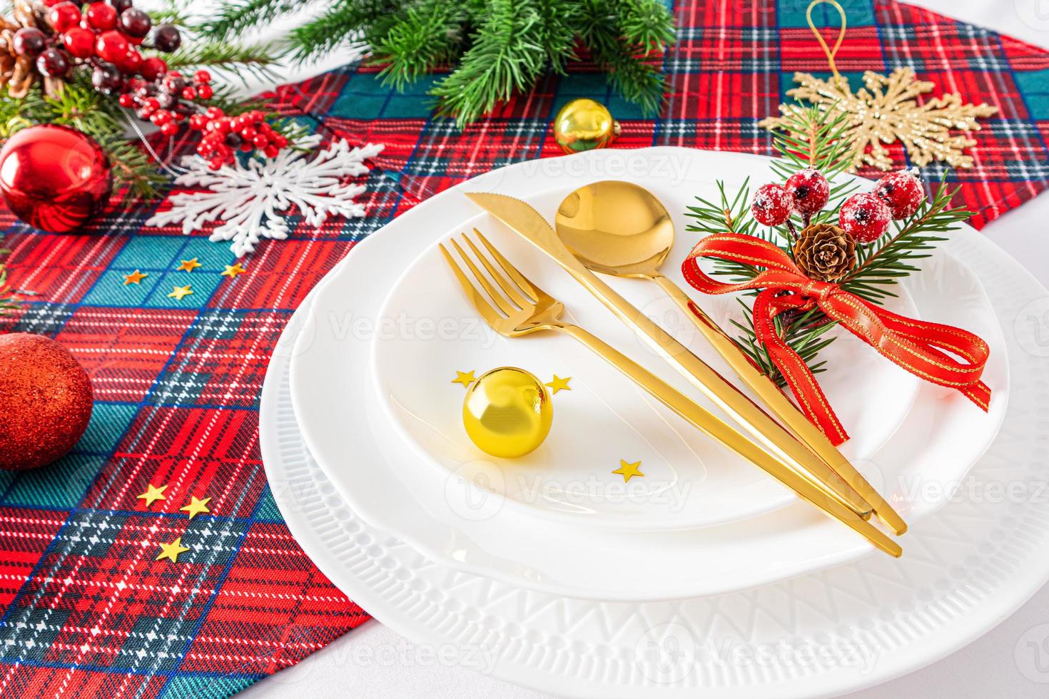 pratos de natal e decorações de natal no fundo tradicional de cor vermelha, verde e branca. talheres de ouro. vista frontal. foto