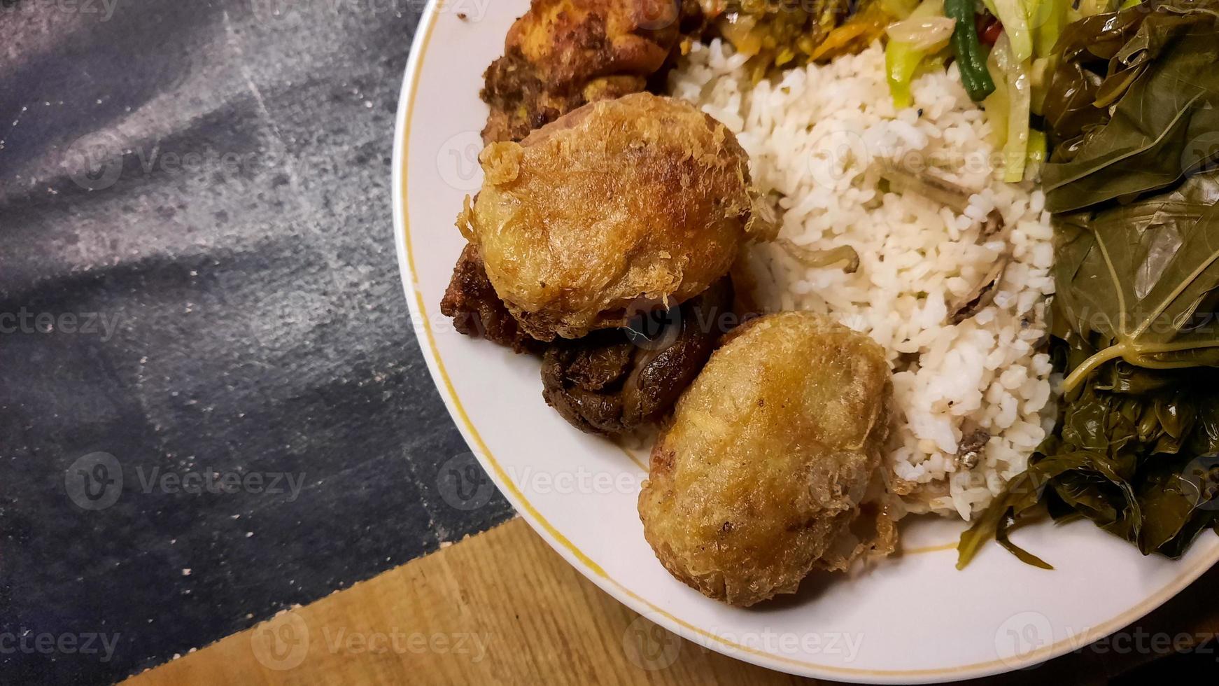 ângulo superior, menu warteg comida tradicional indonésia, com bolos de batata e folhas de mandioca frescas 01 foto