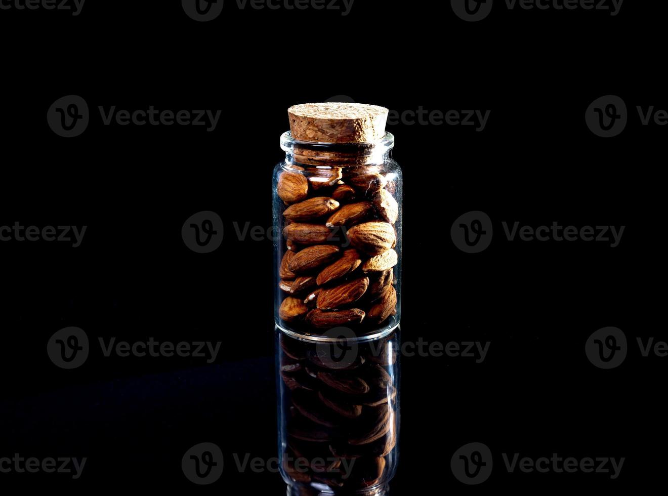 amêndoa descascada no balde de copo de vinho jar em um fundo preto isolado. linha de tigelas com amêndoas, vista frontal. foto