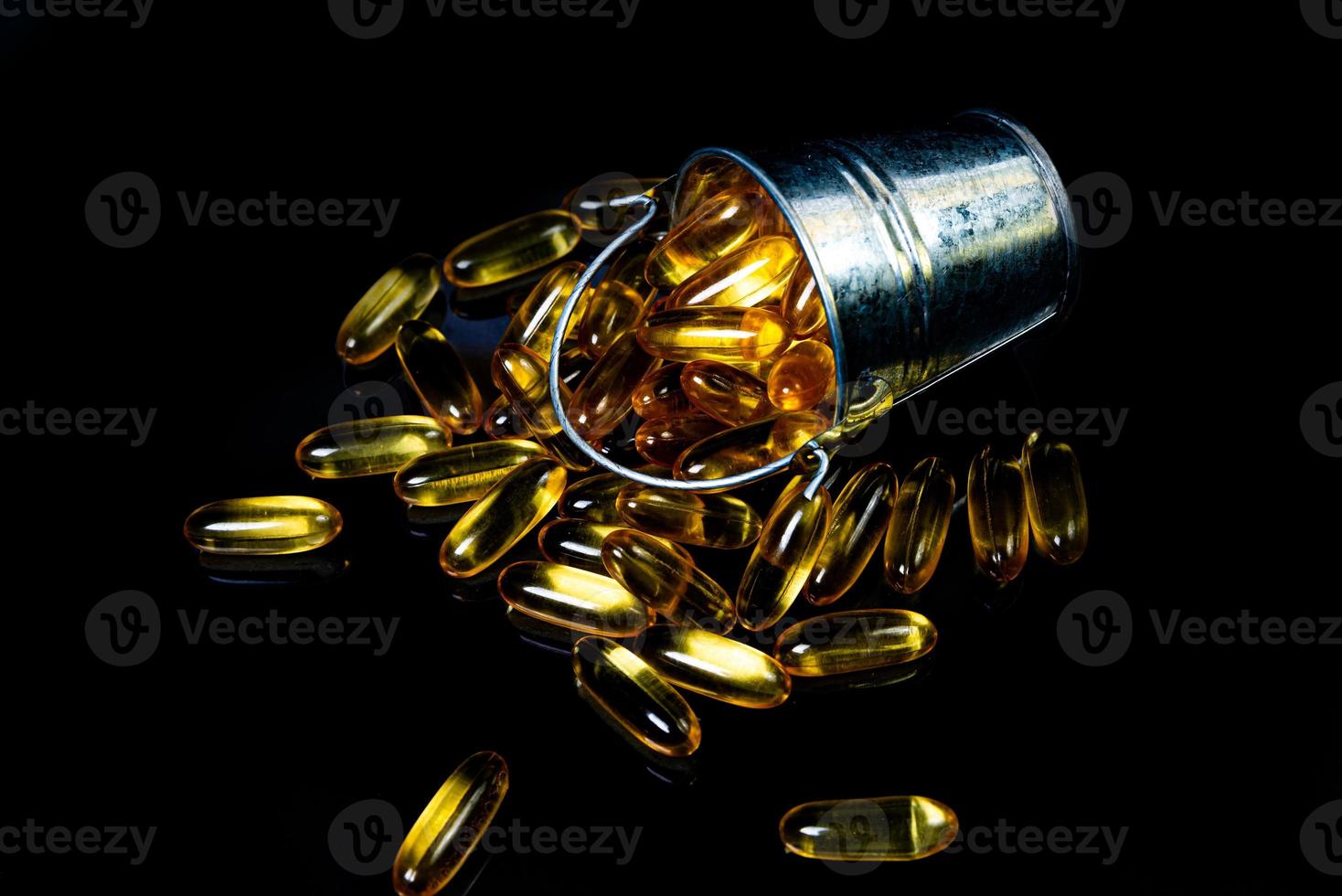 cápsulas de óleo de peixe. comprimidos de ômega 3 amarelos em frasco no preto escuro. cápsulas de óleo de peixe em copo de vinho. em jarra. em ampolas de balde foto