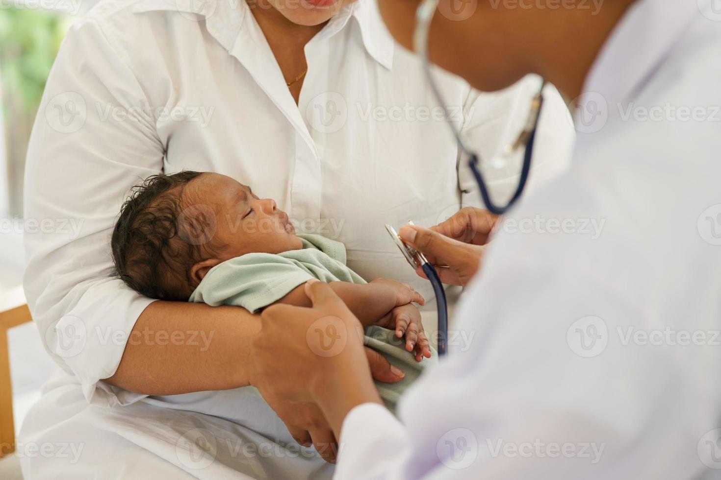 um bebê recém-nascido de um mês de idade mestiço afro-tailandês, visitando o médico para exame de saúde com estetoscópio na clínica pediátrica. consulta de conceito, check-up, enfermeira, cura infantil. foto