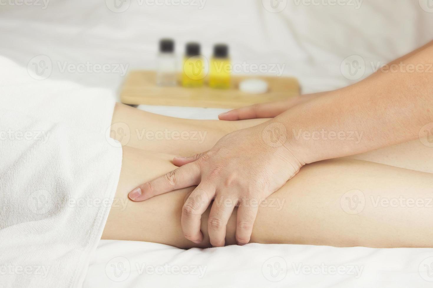 a mão do massagista massageia os músculos da panturrilha da jovem no salão spa. conceito de cuidados de saúde, relaxamento ou uso de produtos naturais para cuidar da pele das pernas foto