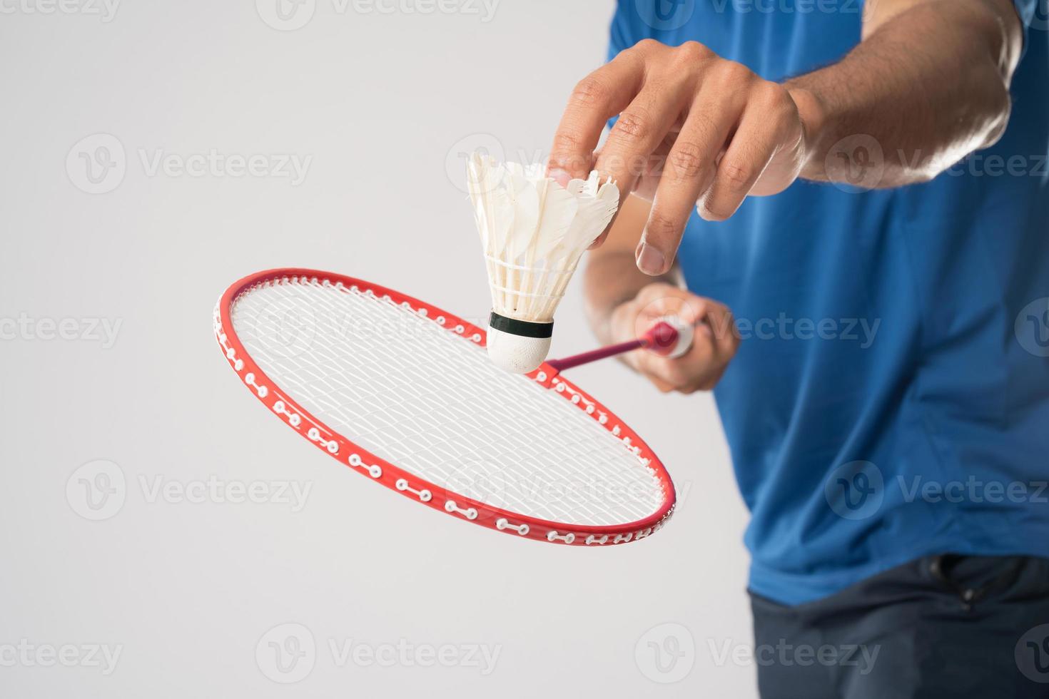 um jogador de badminton em roupas esportivas fica segurando uma raquete e peteca. foto
