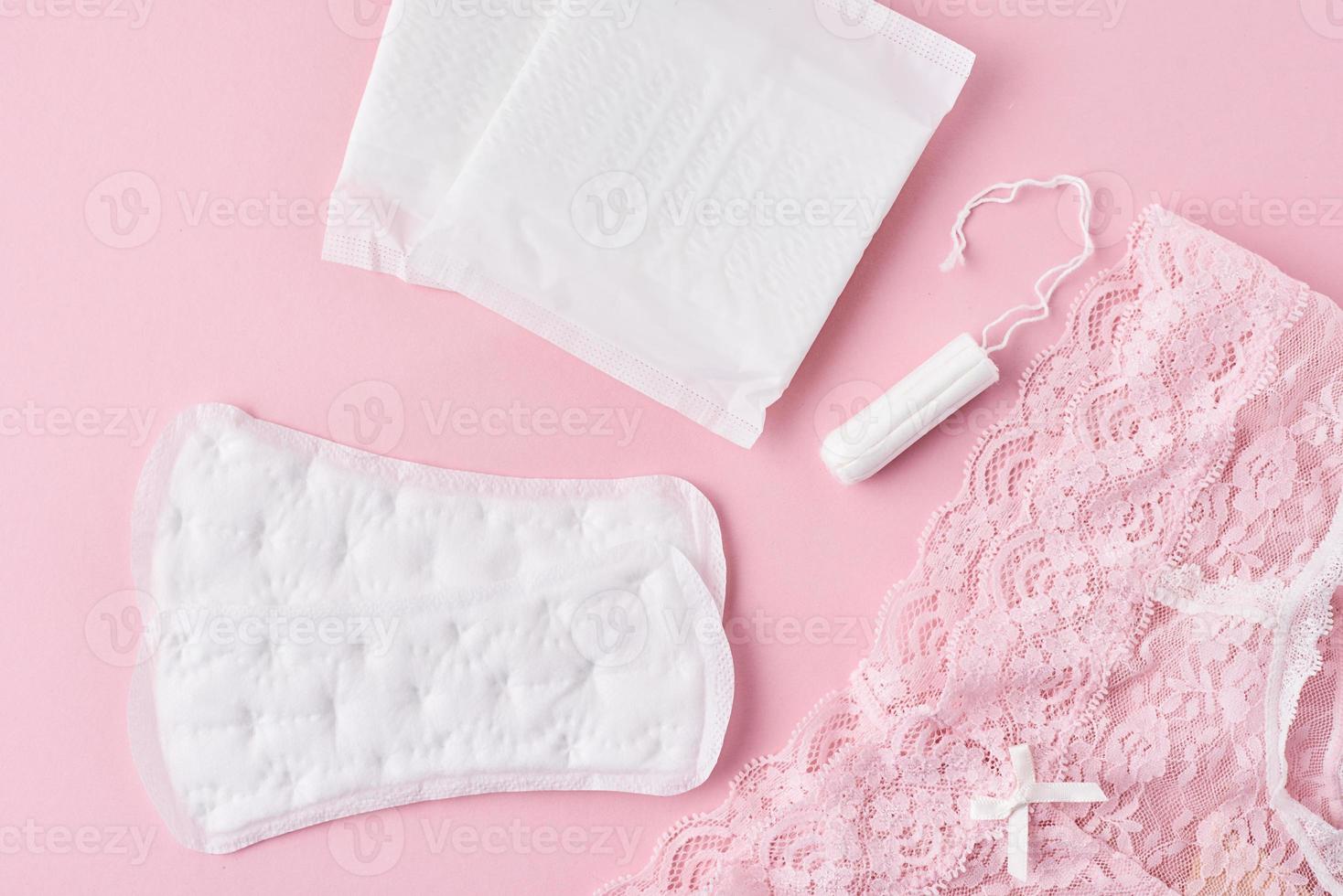 absorvente higiênico, copo menstrual, tampão e calcinha em um fundo rosa foto