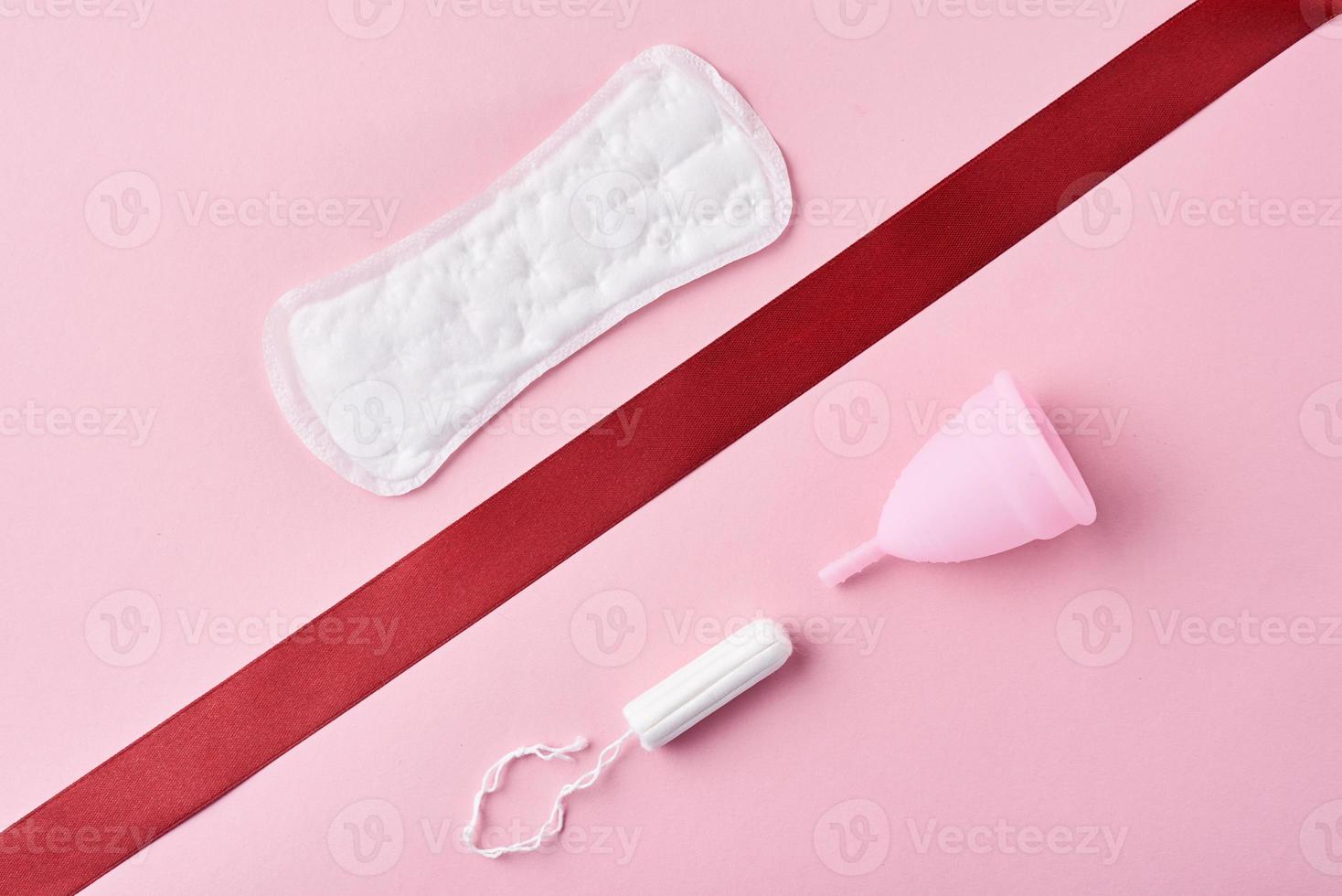 absorvente higiênico, copo menstrual e tampão em um fundo rosa foto