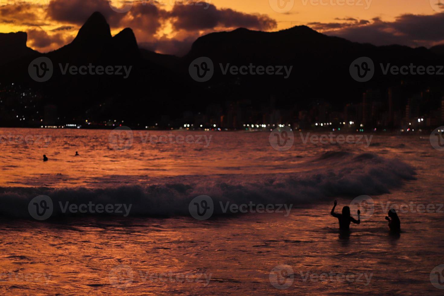 rio de janeiro, rj, brasil, 2022 - pessoas em silhueta assistem o pôr do sol na rocha do arpoador, praia de ipanema foto
